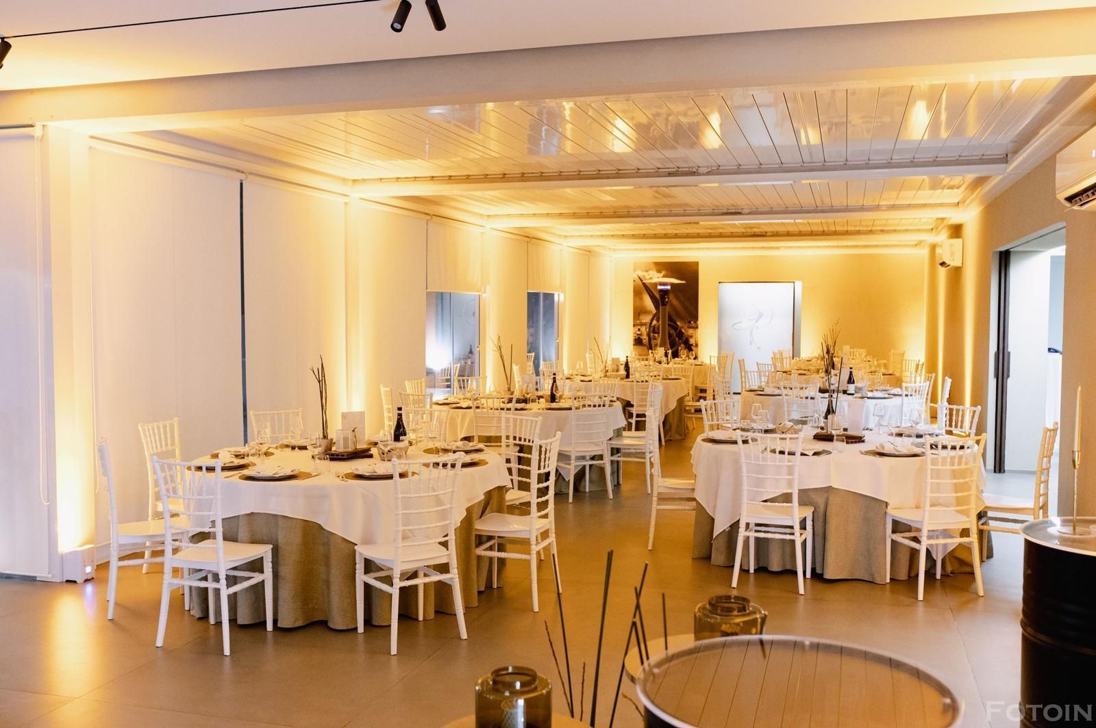 Elegante sala per banchetti con tovaglie bianche, illuminazione dorata e tavoli apparecchiati per un evento.
