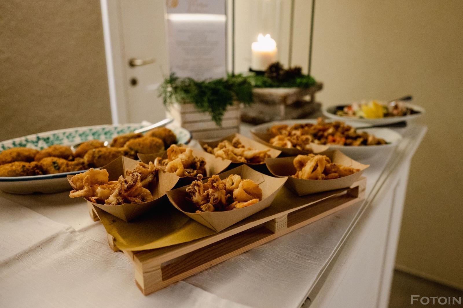 Vassoi di cibo fritto su un tavolo da banchetto con un centrotavola a candela accesa.
