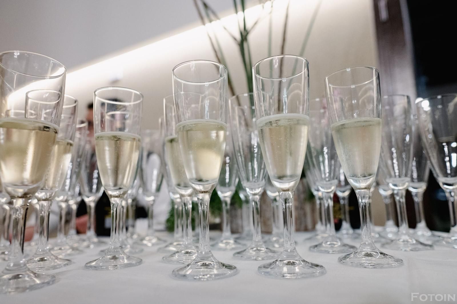 Su un tavolo, file di flûte da champagne piene di spumante, pronte per una festa.