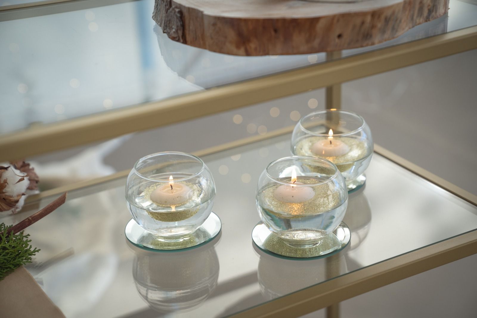 Tre lumini accesi in portacandele di vetro su un vassoio a specchio