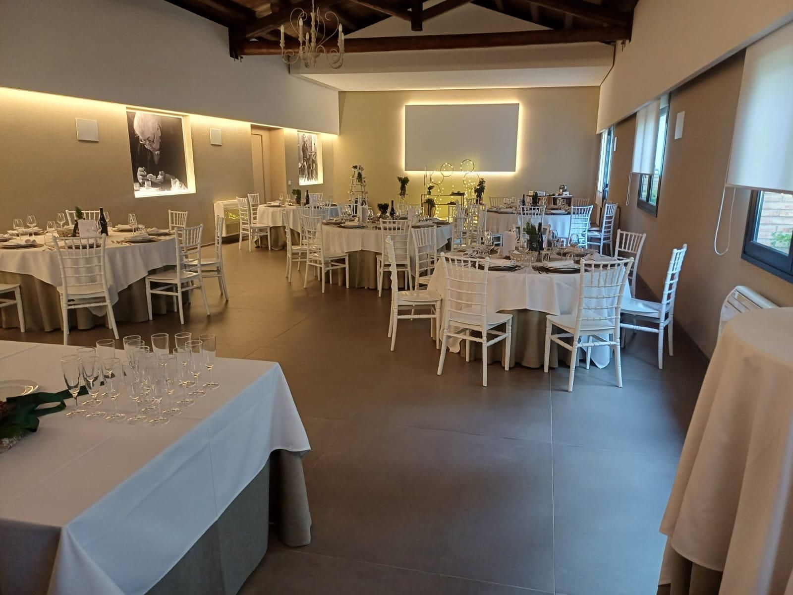 Elegante sala per banchetti con tavoli rotondi, tovaglie bianche e luci soffuse a parete in un ambiente spazioso.