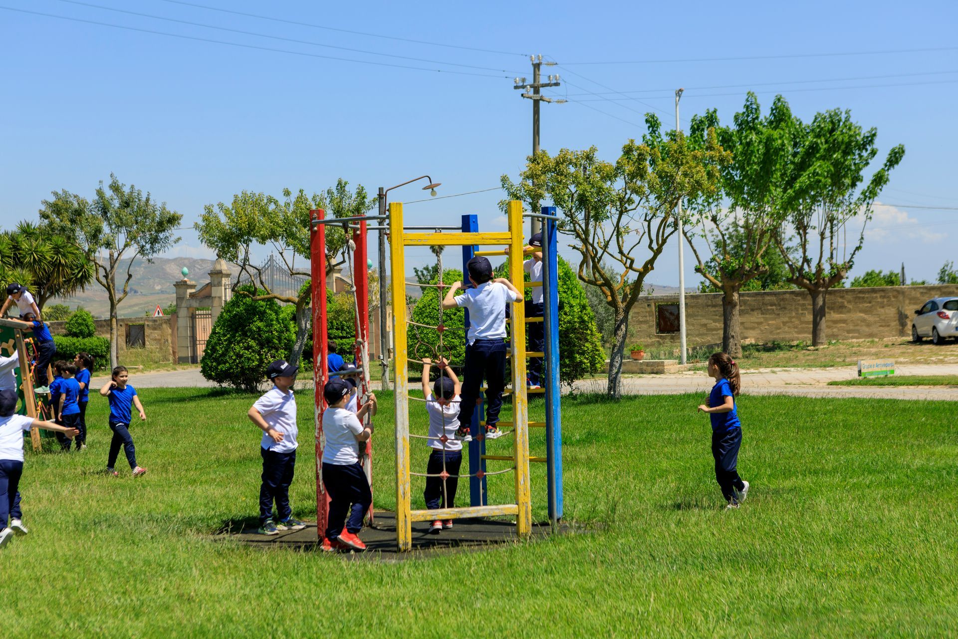 Bambini che giocano su colorate strutture all'aperto in un parco erboso in una giornata di sole.