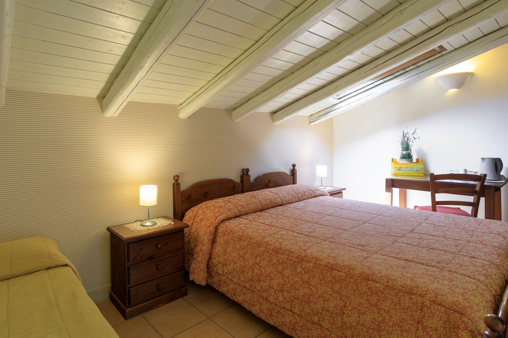 Accogliente camera da letto mansardata con due letti singoli, lampada da comodino.