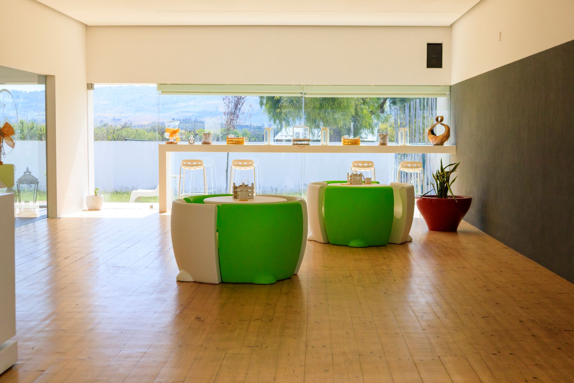 Salotto moderno con sedie verdi, pavimento in legno e finestre con vista sull'oceano.