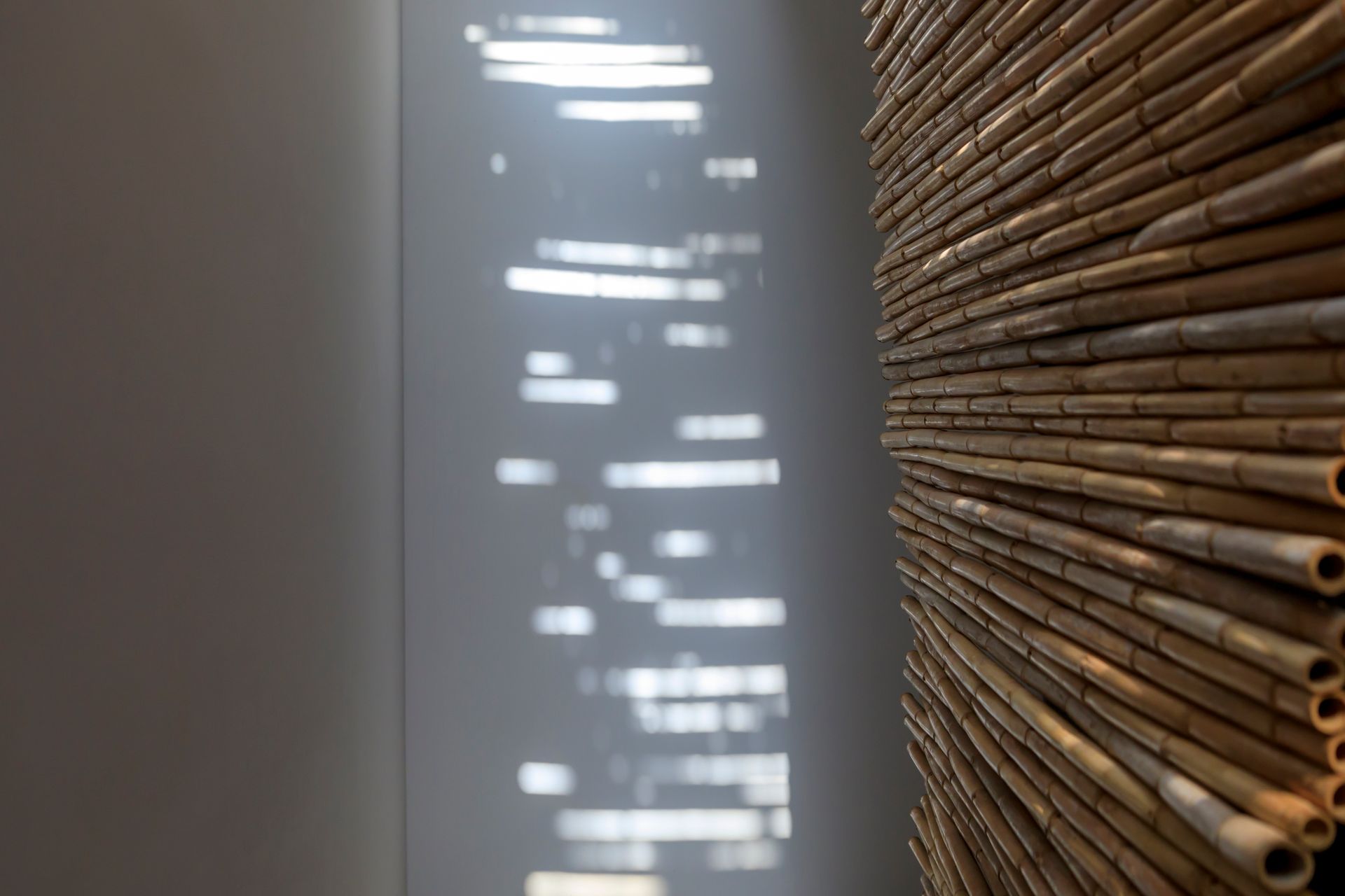 Tende di legno accanto a una parete con luce solare intensa che proietta riflessi verticali