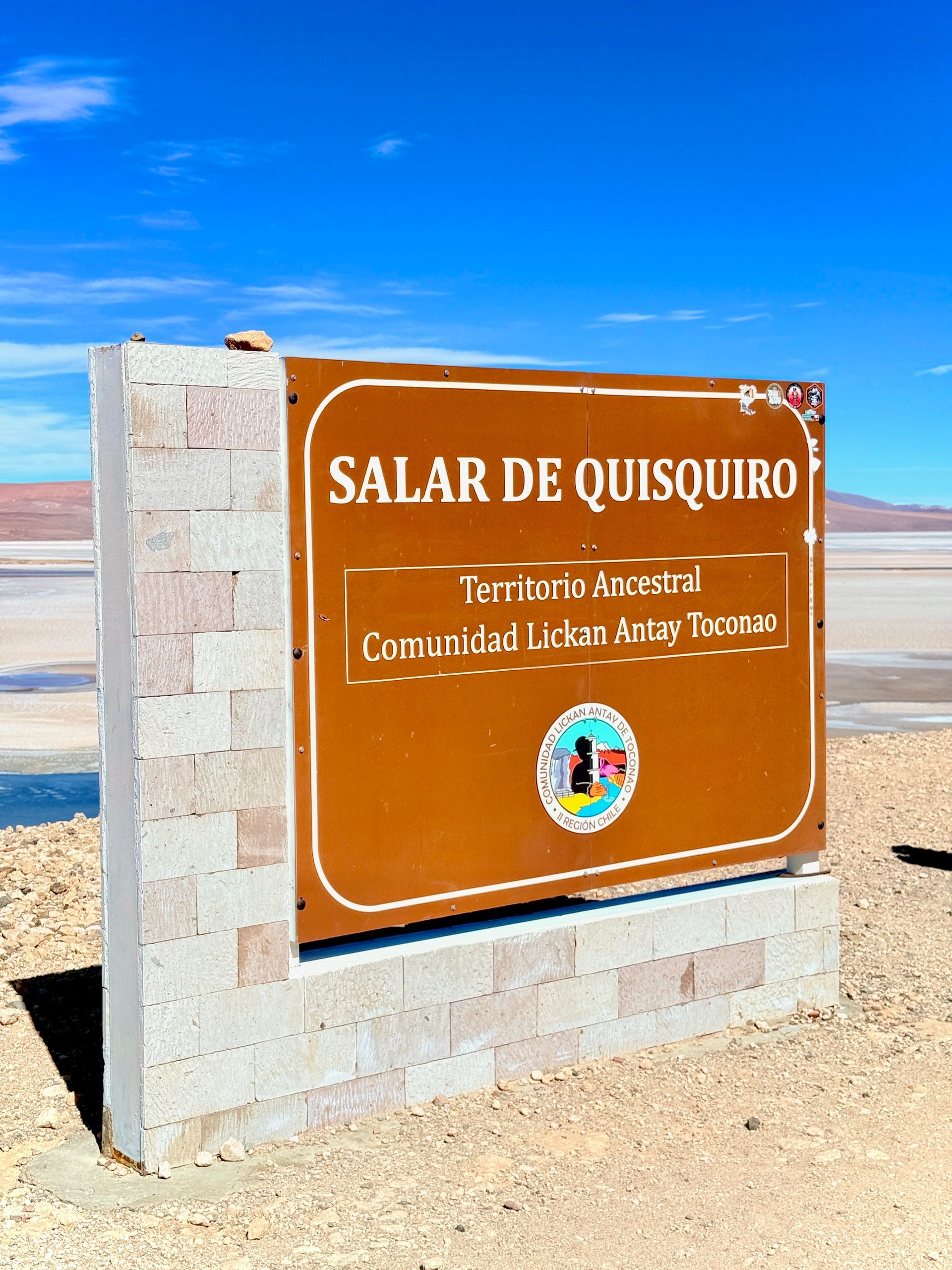 Señal del Salar de Quisquiro contra el cielo azul y el paisaje desértico.