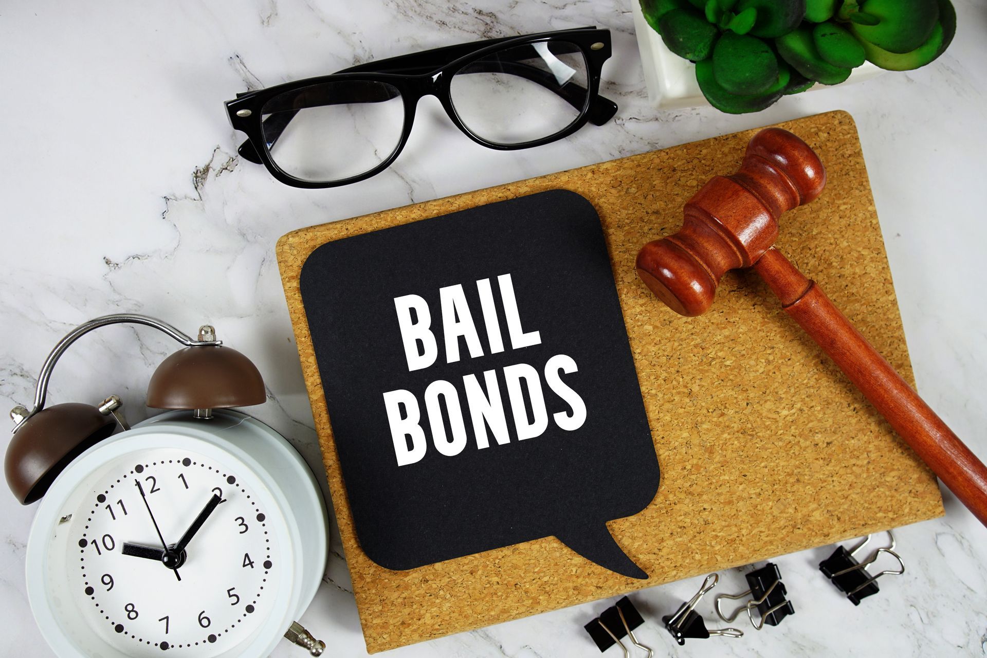 Bail bonds text showcasing 24 hour bail bonds service with gavel and alarm clock on marble.