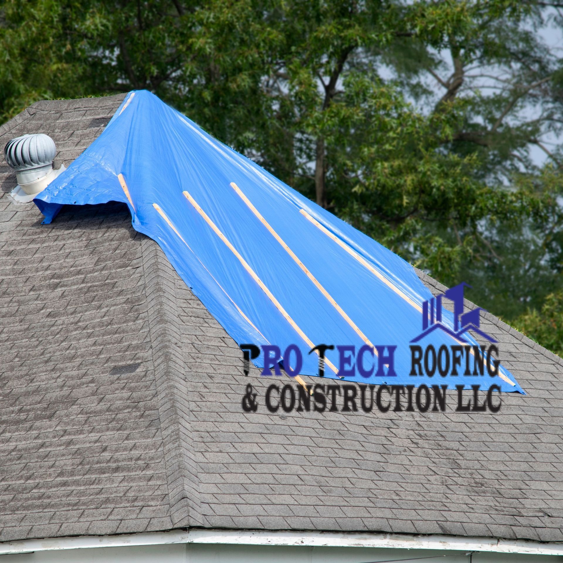 A roof with a blue tarp on it that says pro tech roofing & construction llc