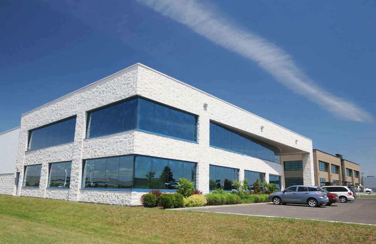 A large white building with a lot of windows and cars parked in front of it.