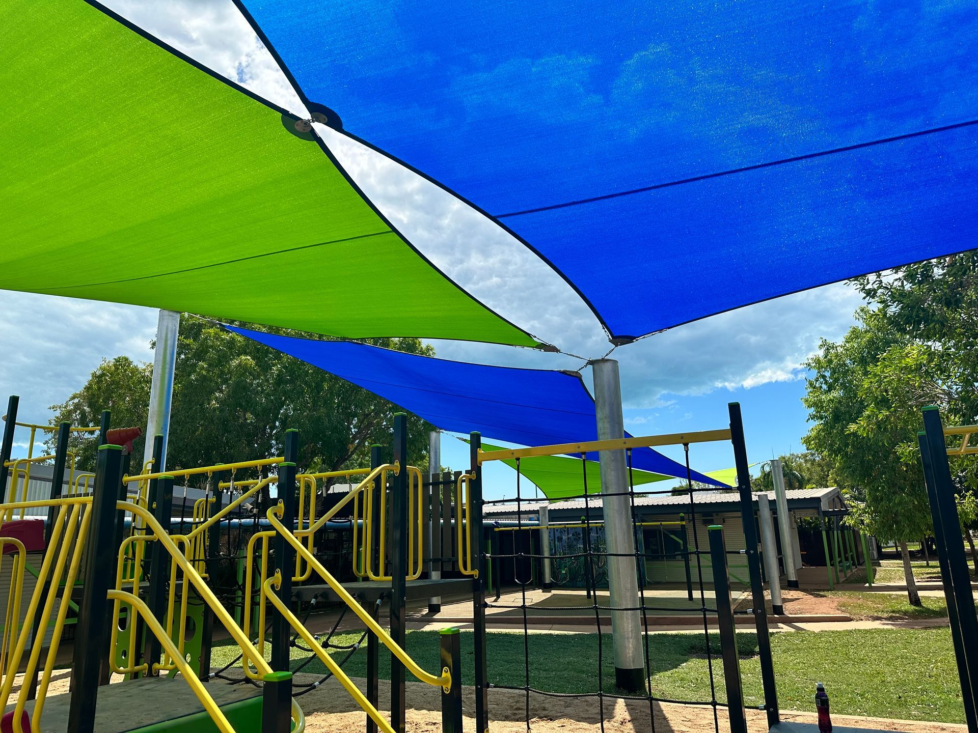 A Blue Umbrella Is Covering A Playground In Front Of A House — Aerosail Engineered Fabric Structures In Winnellie, NT