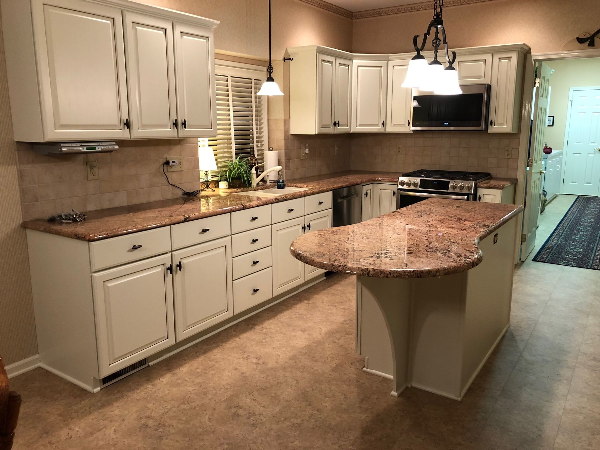 Cream-colored kitchen with granite countertops, island, cabinets, and appliances.