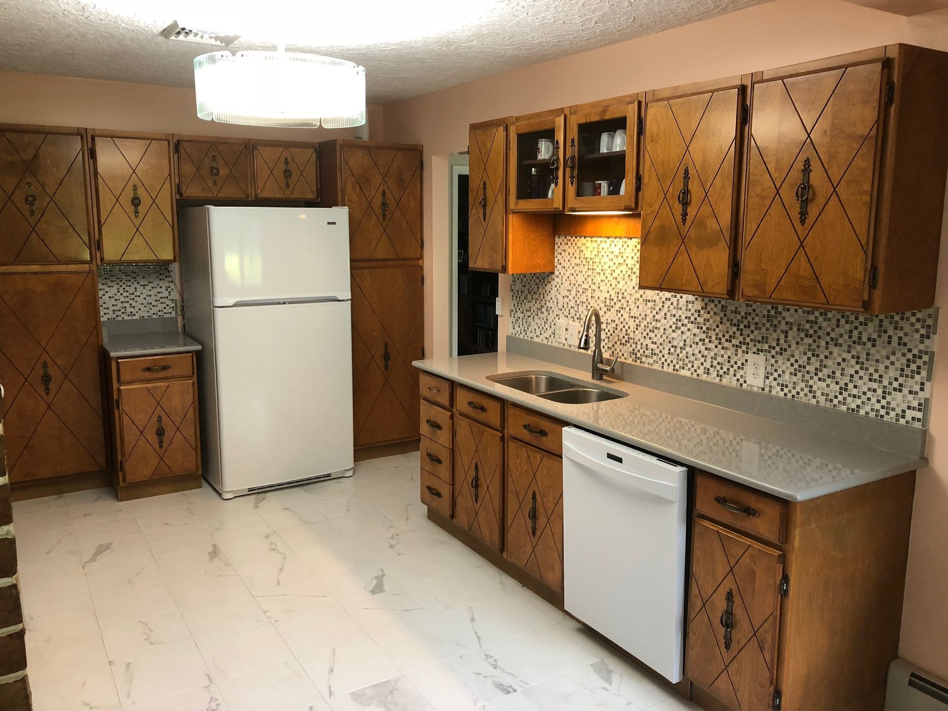 Kitchen with brown cabinets, white appliances, and a light gray countertop.