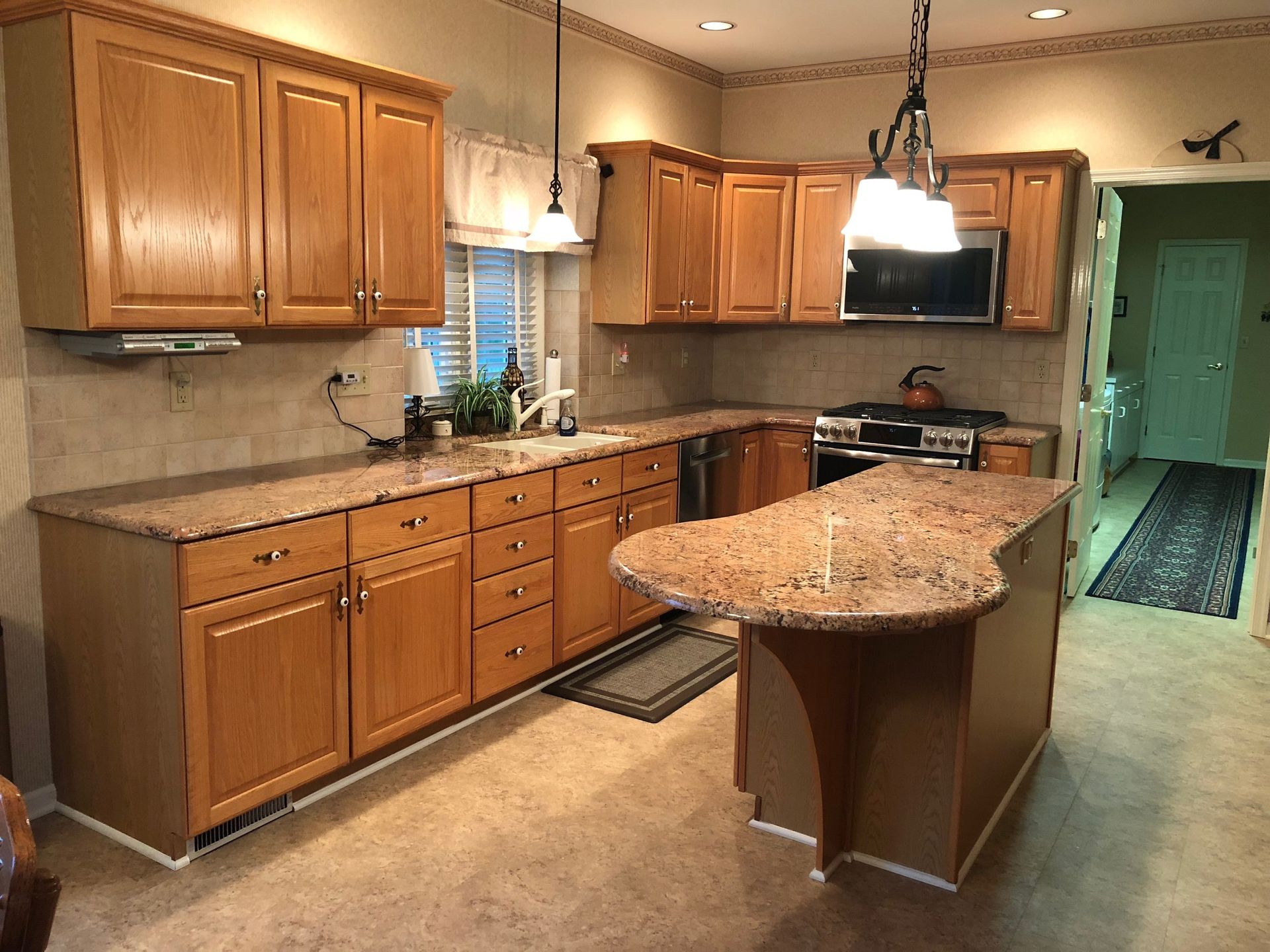 A kitchen with light brown cabinets, granite countertops, and a central island.