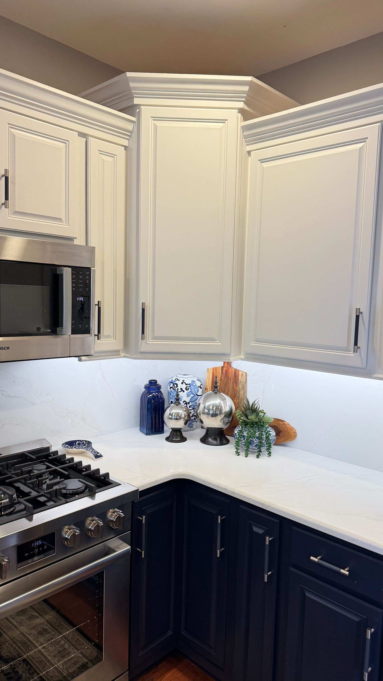 Kitchen with white upper cabinets, navy blue lower cabinets, and a white countertop with decor.