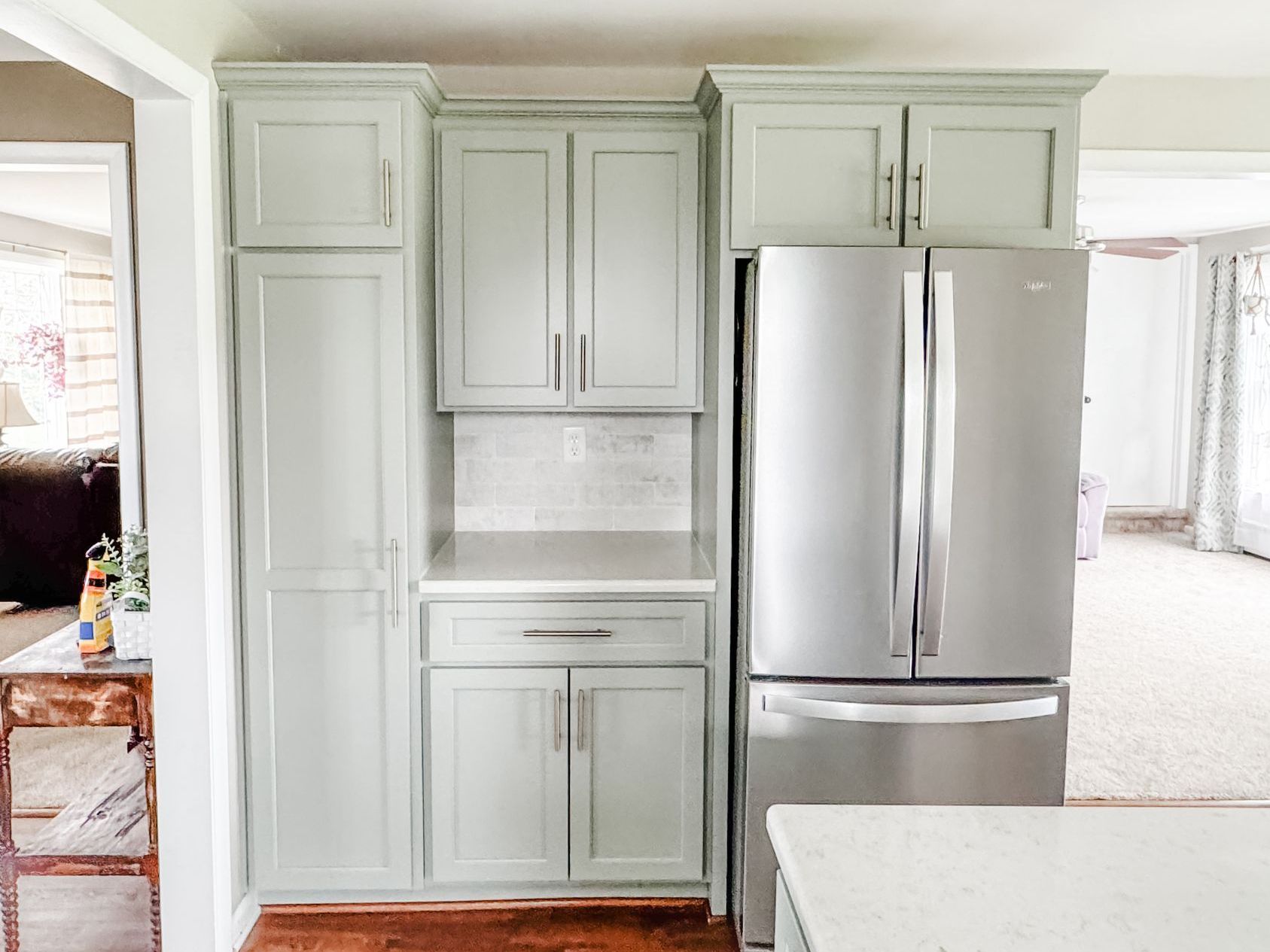 Light green kitchen cabinets with stainless steel refrigerator.