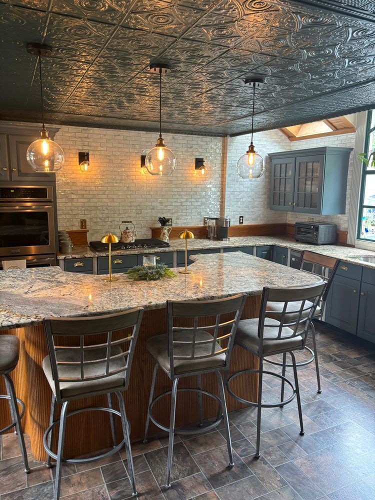 Kitchen with a large island, brick wall, gray cabinets, and pendant lights.