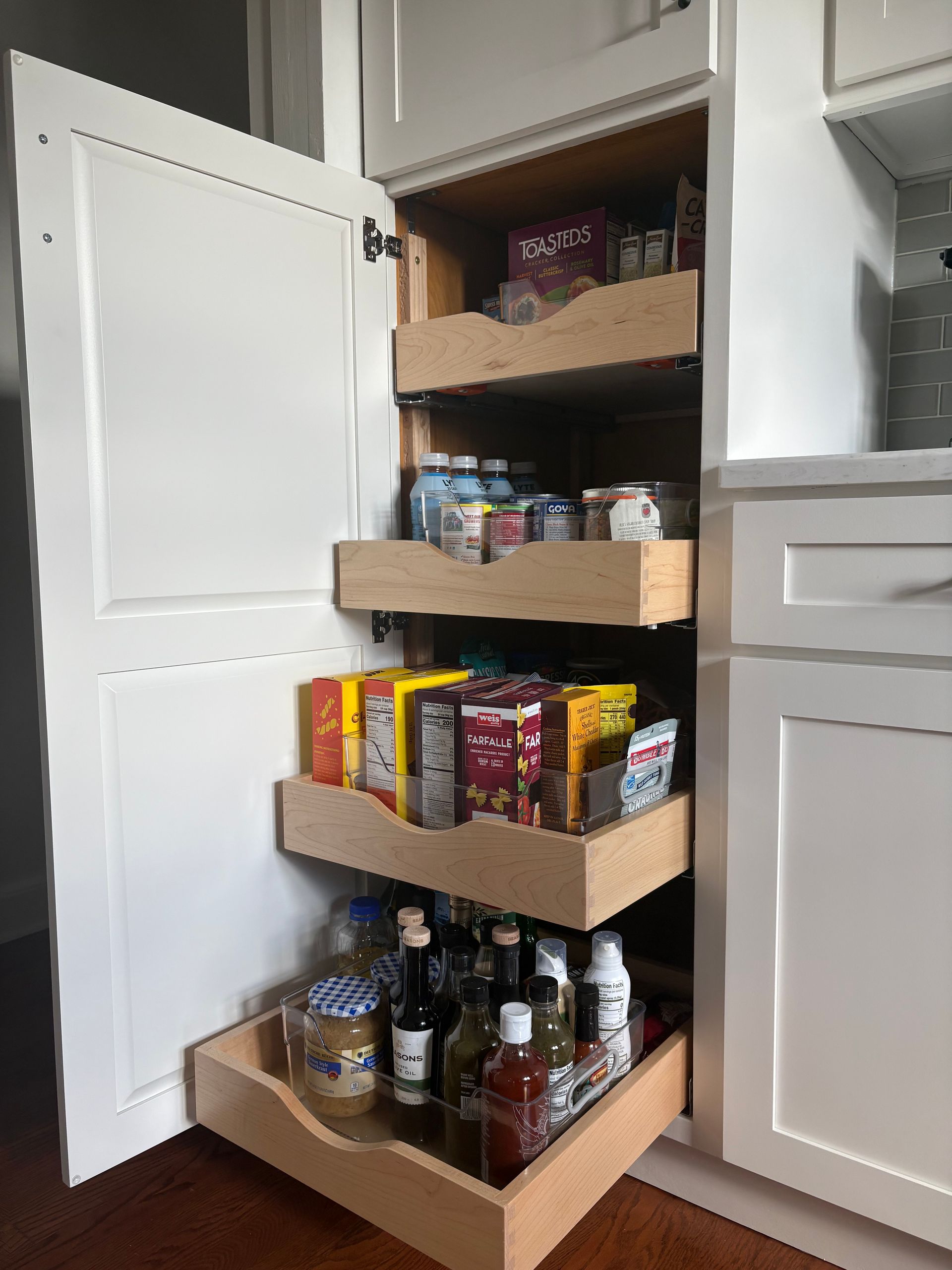 Pantry cabinet with pull-out shelves filled with jars of spices and dry goods.