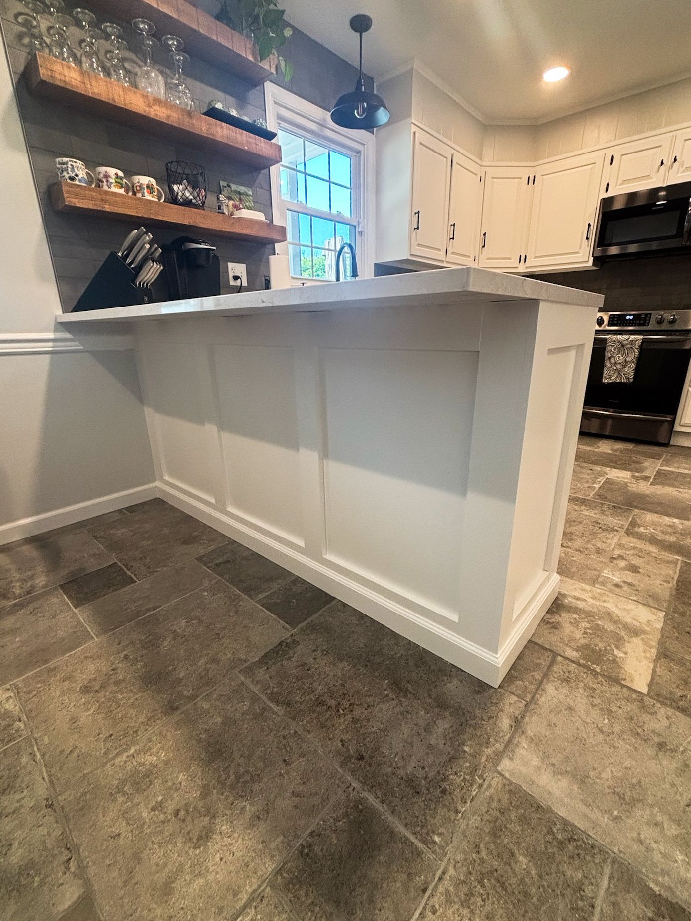White kitchen island with paneling, next to tile flooring.