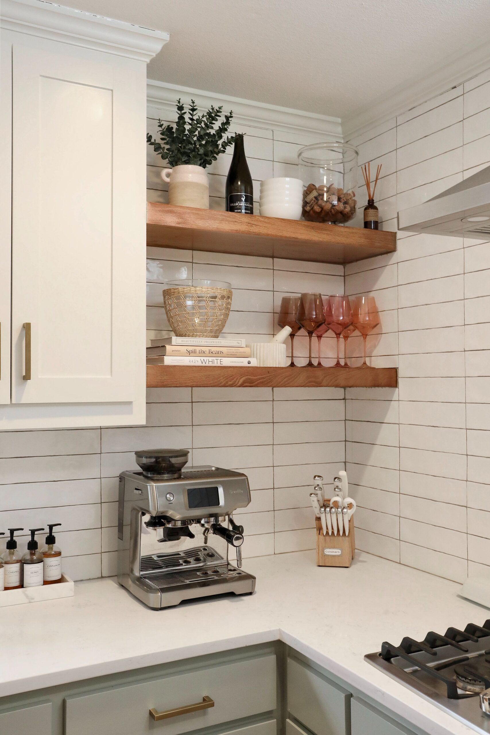 Kitchen with open shelves, espresso machine, and white and green cabinetry.