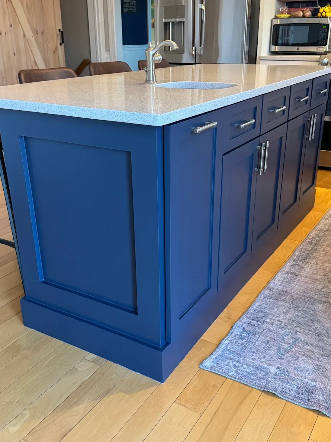 Blue kitchen island with a light-colored countertop. Silver hardware and a sink are visible. Wooden floor.