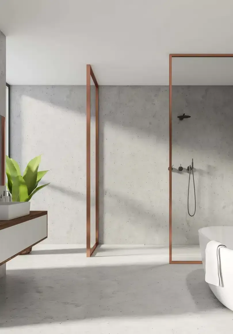 Modern bathroom with concrete walls, copper shower frame, white tub, and vanity with a plant.