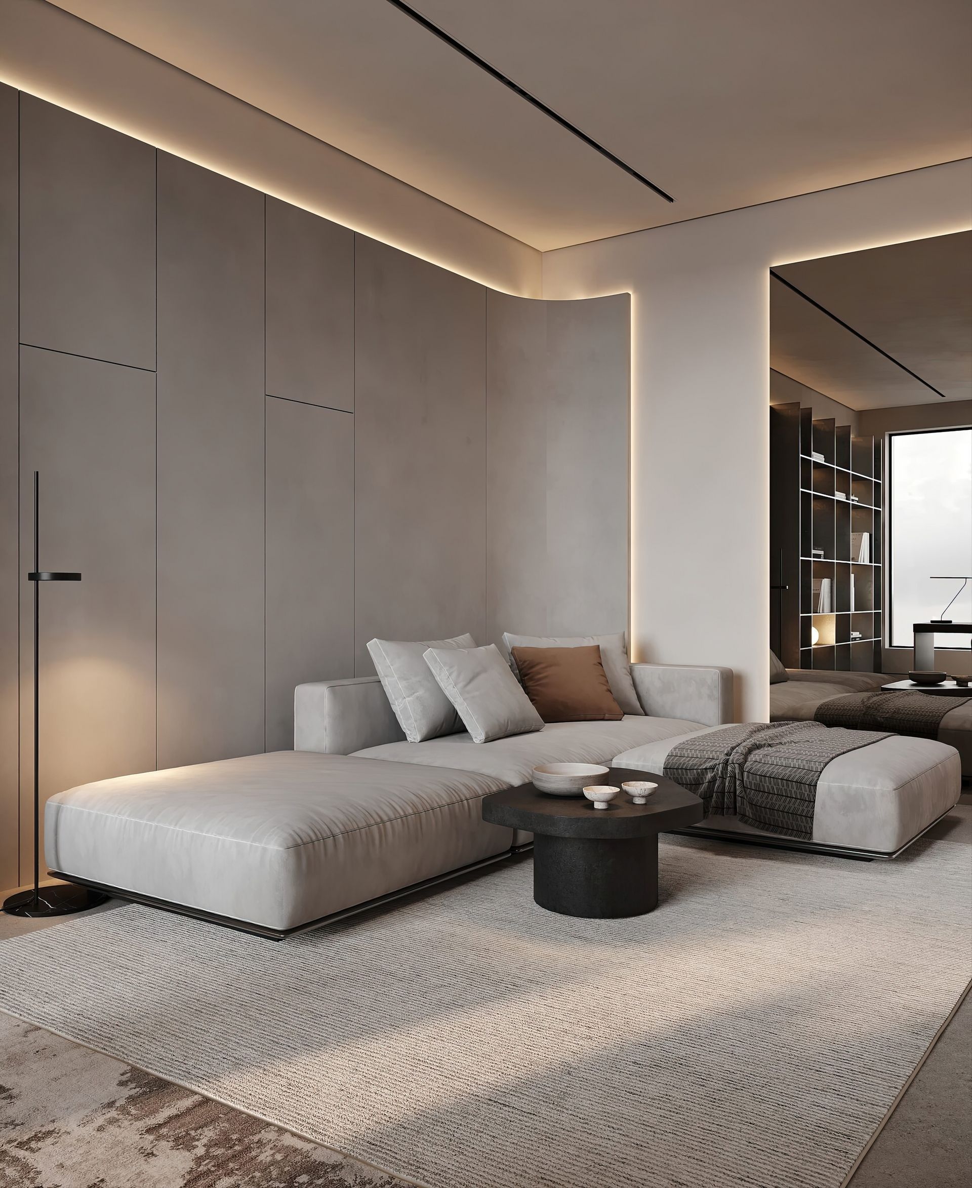 Modern living room with light gray sectional sofa, ottoman, and dark coffee table on a neutral rug.