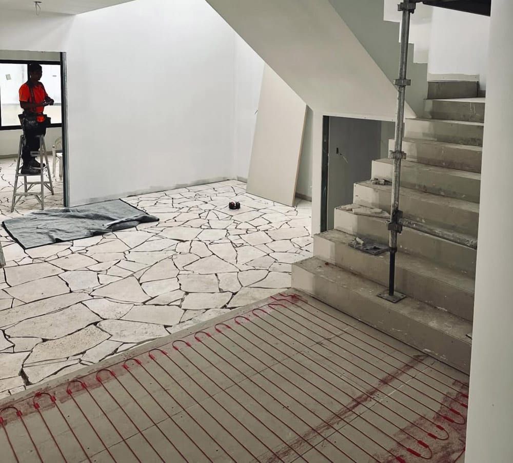 Interior under construction with tiled floor, staircase, and a person working by a window.