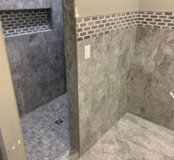 A bathroom with gray tiles and a walk in shower.