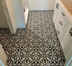 A black and white tile floor in a bathroom with white cabinets.