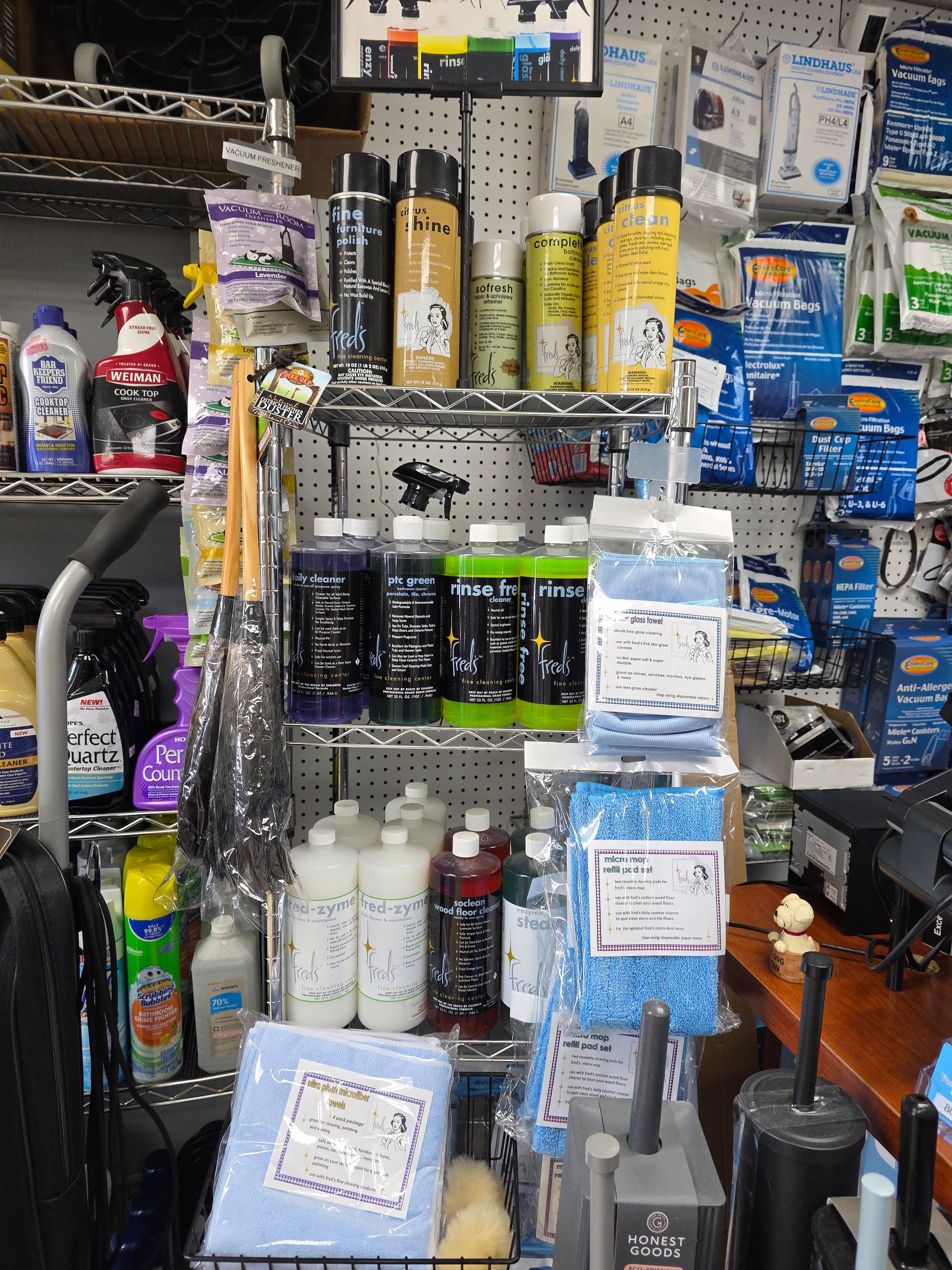 Shelves filled with various cleaning supplies, including spray bottles, liquids, and cleaning cloths in a retail store.