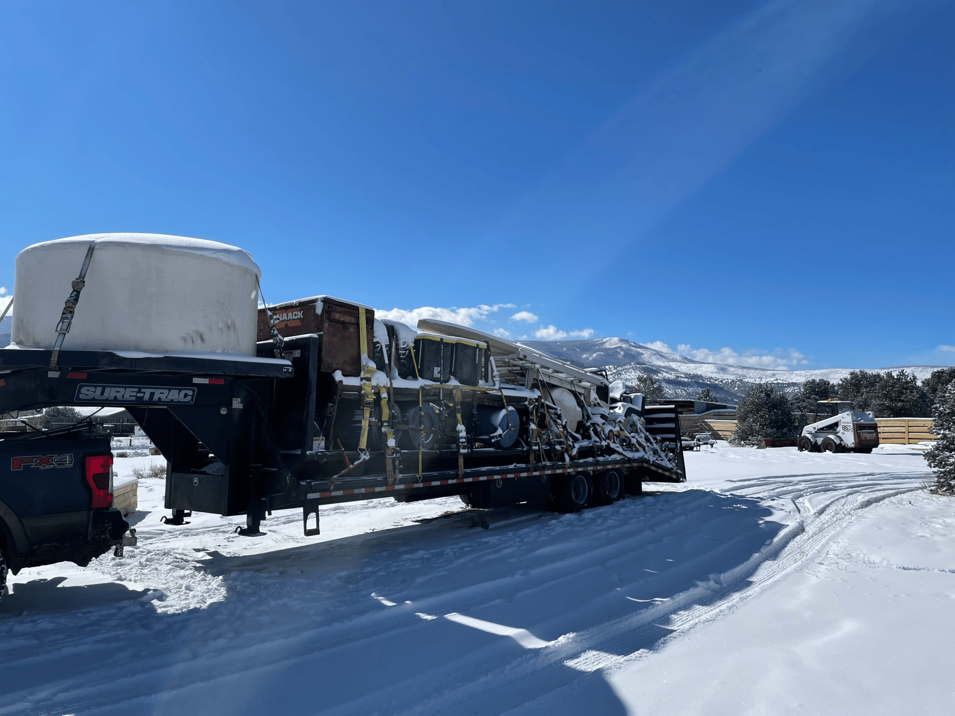 hotshot trucking in the snowy conditions with a full heavy duty load of construction equipment
