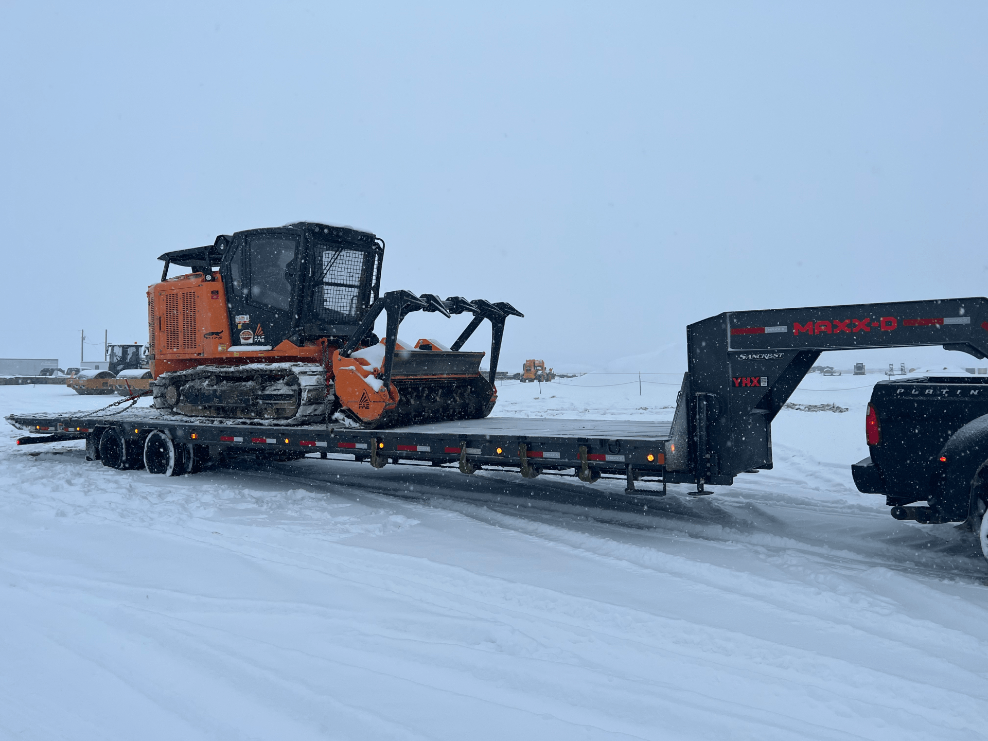 skidster with attachment on flatbed trailer in snowy conditions 
