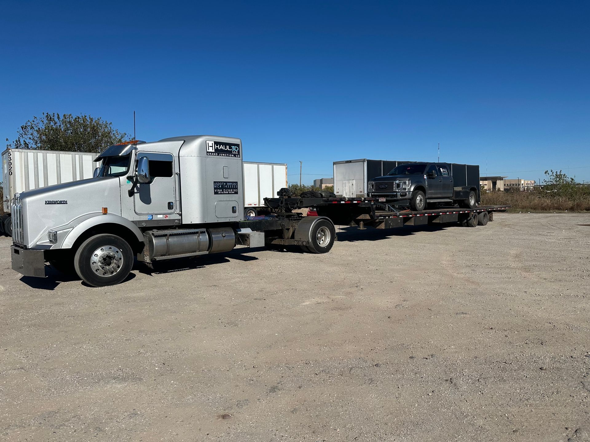 vehicle and construction equipment hauled through denver on flatbed trailer