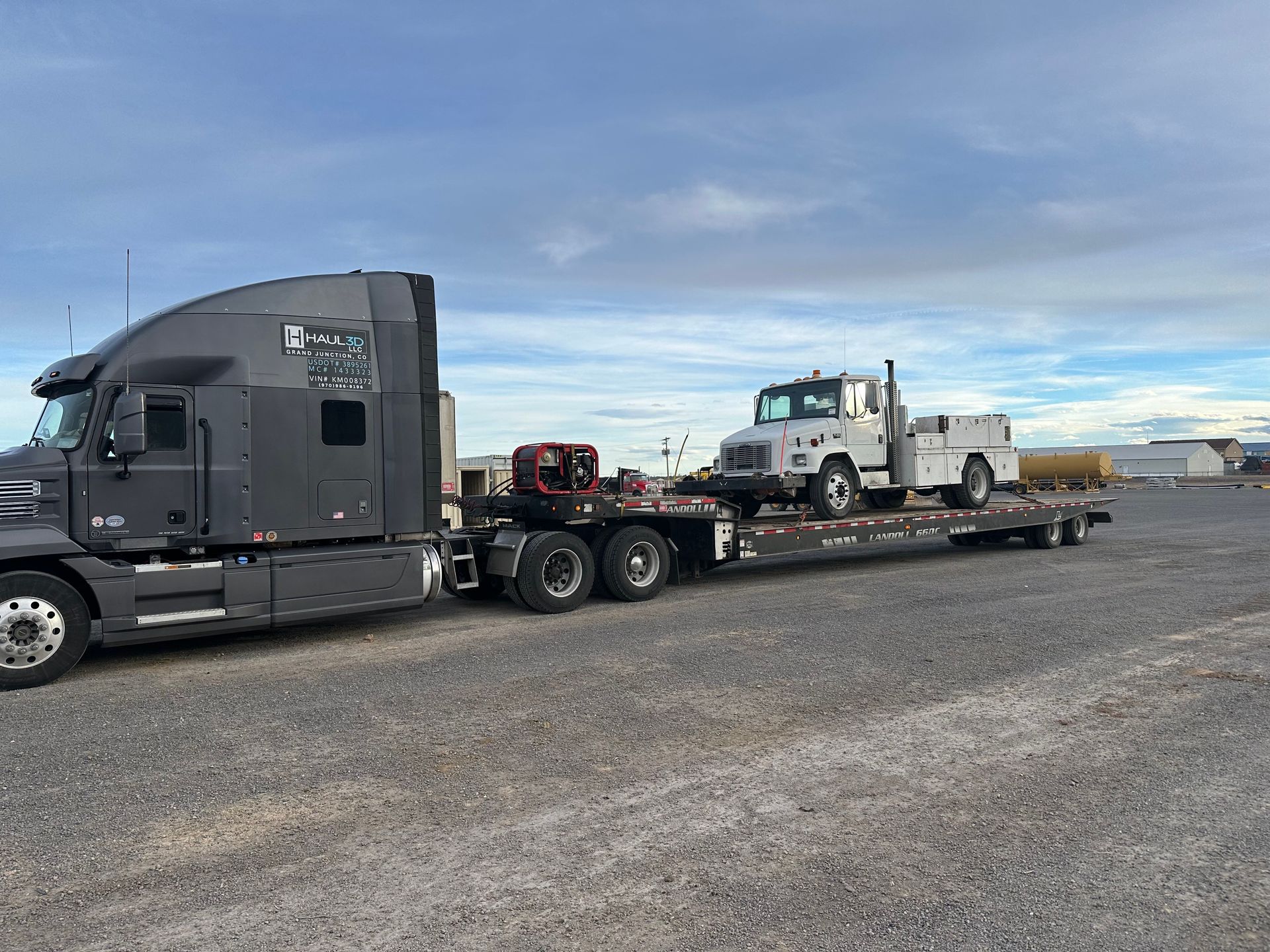 car, skidster, and cart being transported on flatbed trailer by haul3d