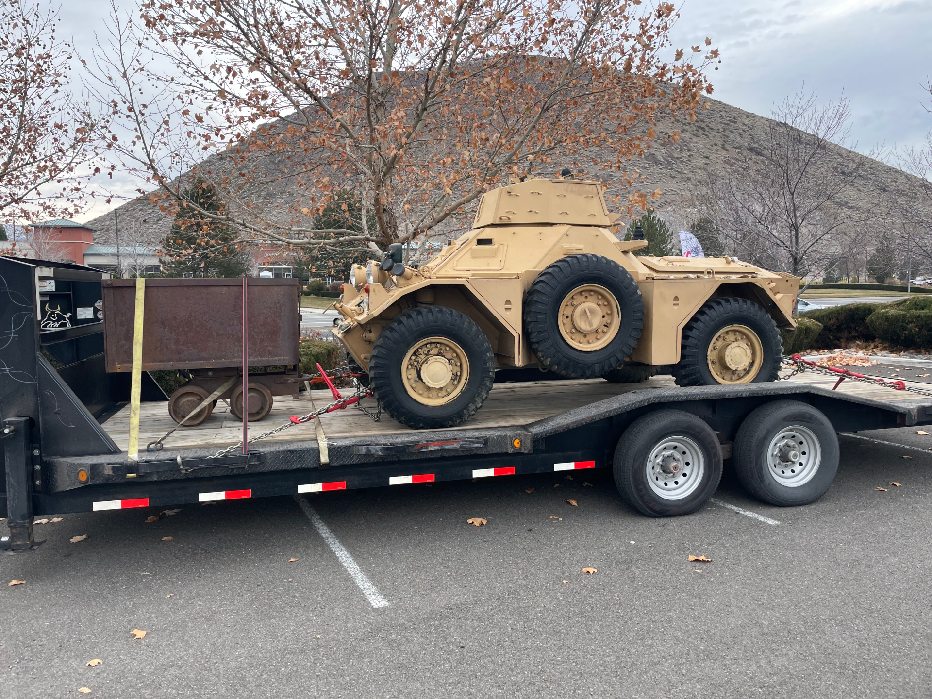 mining cart and tank strapped to gooseneck trailer to be transported