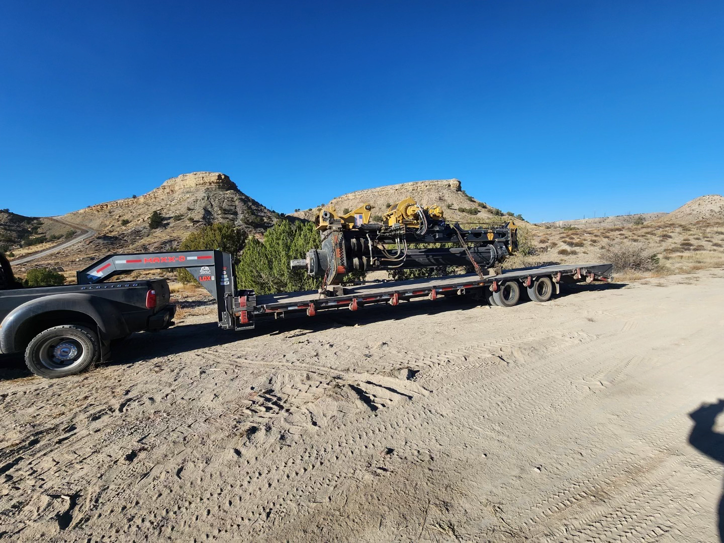 construction equipment on flatbed gooseneck trailer in the dirt