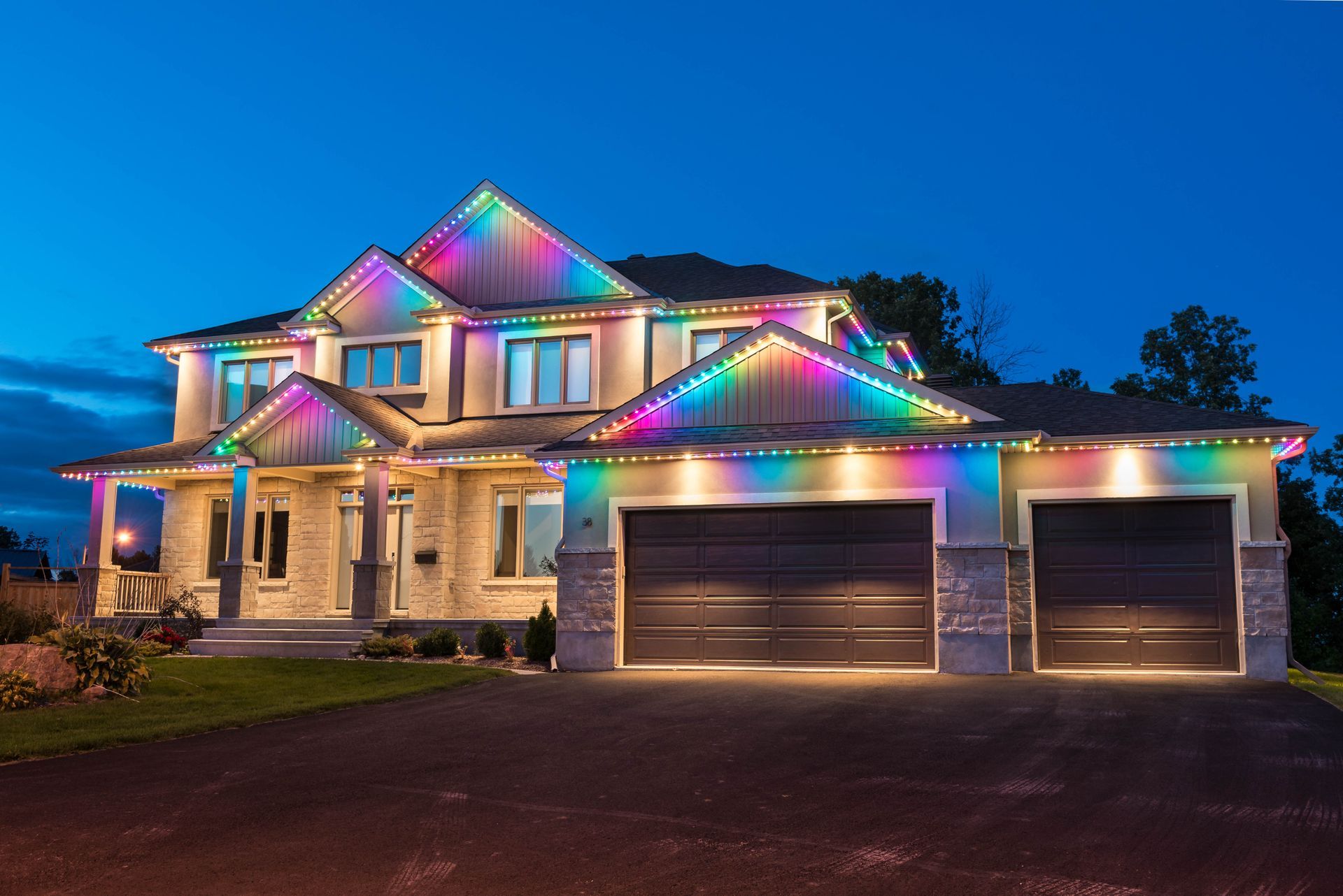 a large house is decorated with rainbow permanent lights at night .
