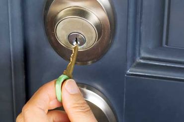 person putting key into lock on door