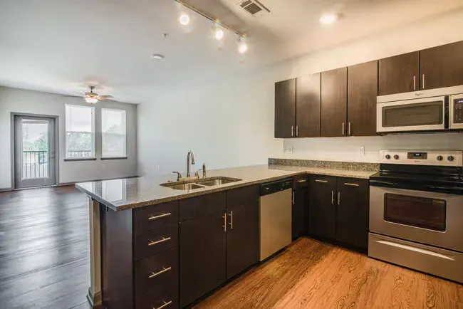 Modern kitchen with dark cabinets, stainless steel appliances, and an island.