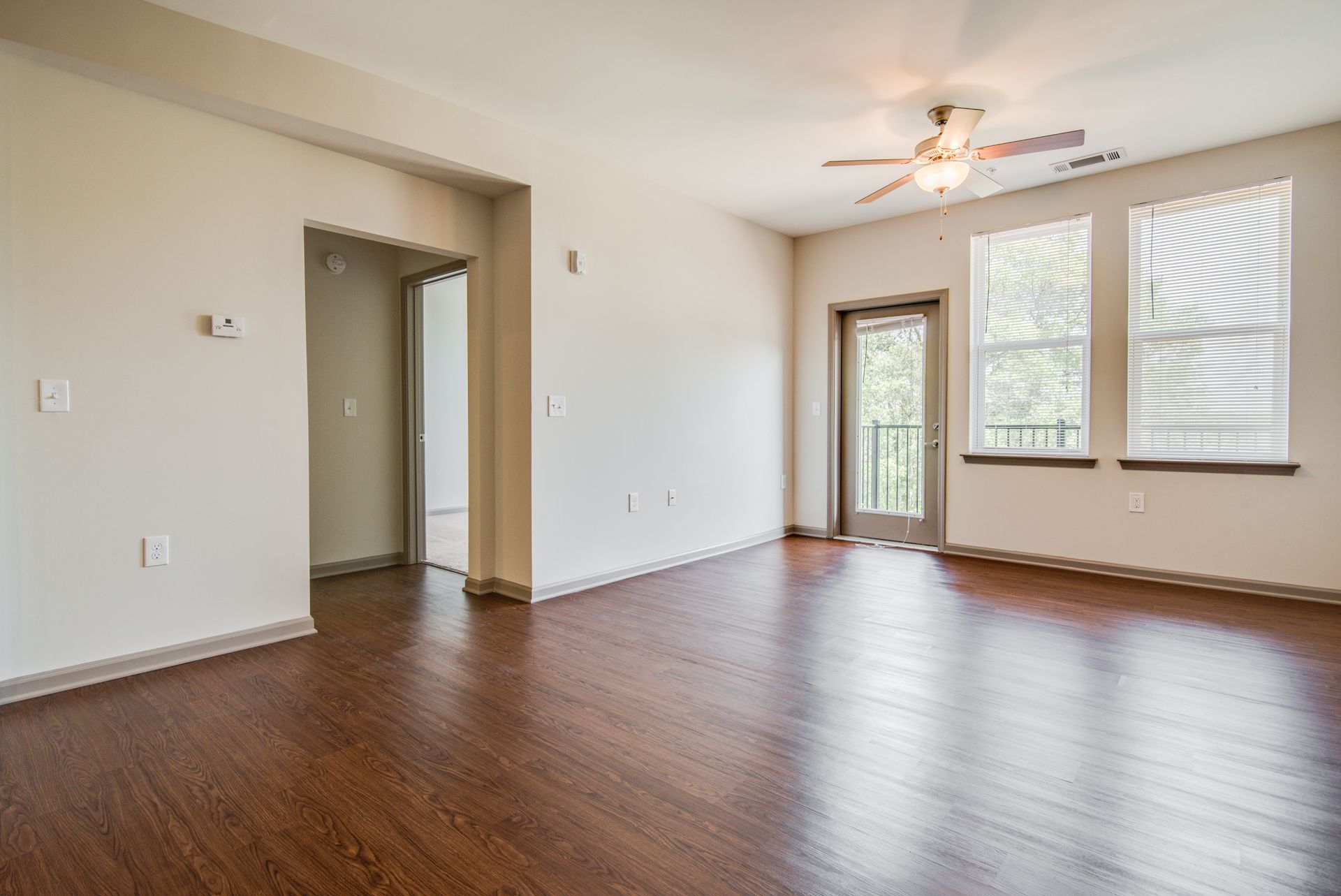 Empty living room with hardwood floors, a doorway, and a balcony door.