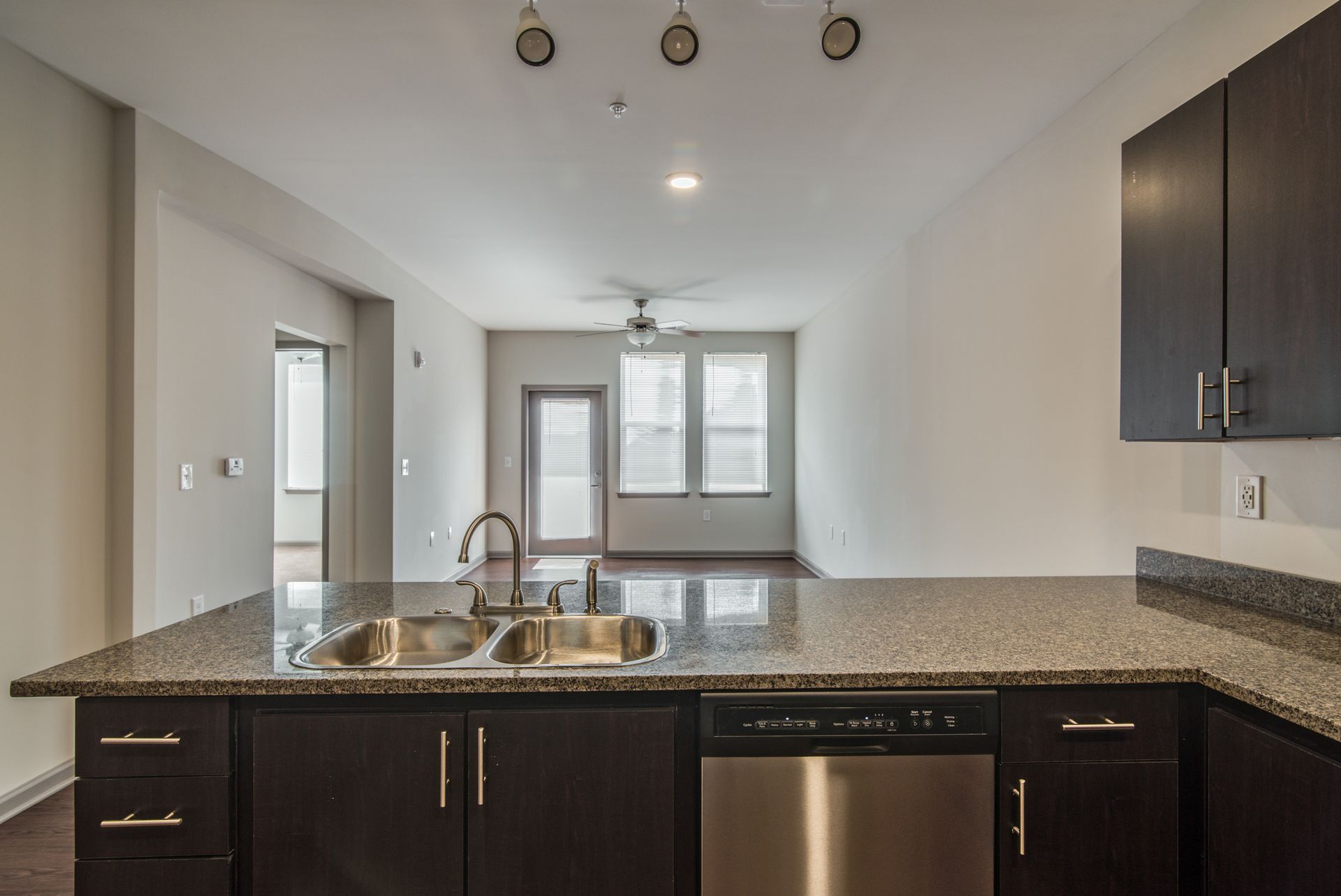 Kitchen with granite countertop, stainless steel sink and appliances, and dark cabinets.