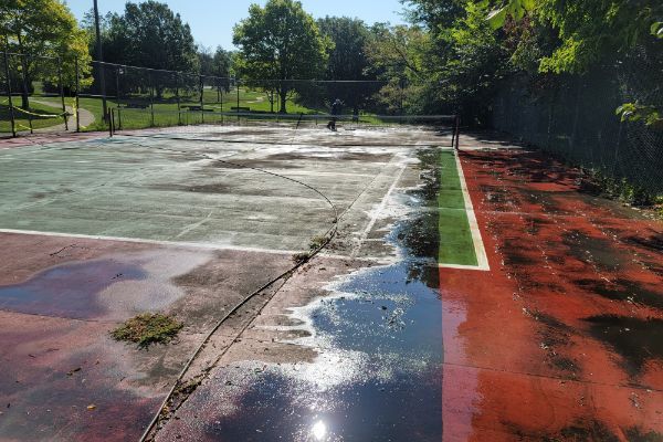 A before and after picture of a tennis court being cleaned.