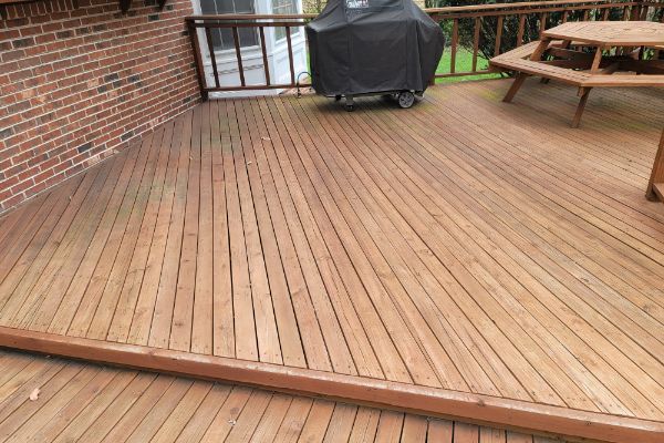 A wooden deck with a grill and a picnic table on it.