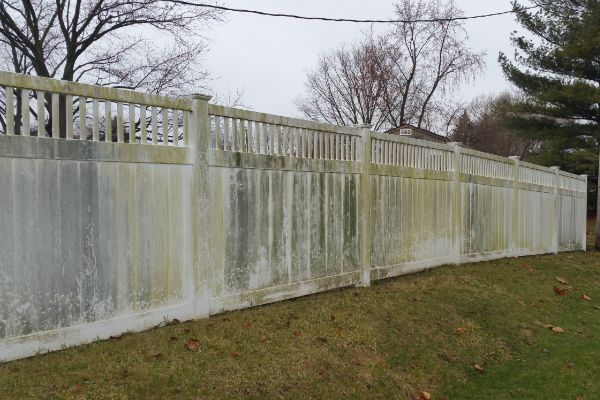 A white fence is sitting on top of a lush green field.