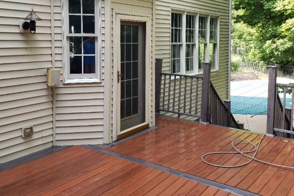 A wooden deck in front of a house with a sliding glass door.