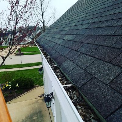 A gutter on the side of a house with a roof in the background