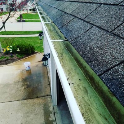 A gutter on the side of a house with a bucket in front of it