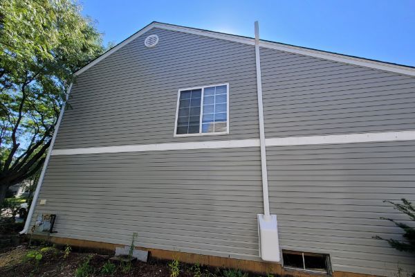 The side of a house with a window and a chimney.