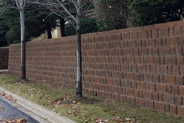 A large brick wall is surrounded by trees and grass.