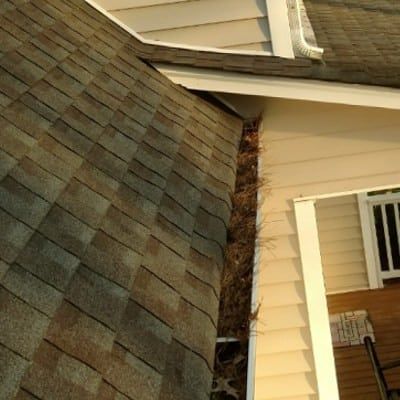 A close up of a roof with a gutter on the side of a house.